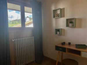 a room with a window and a desk with a radiator at Spacious flat facing Mont Blanc in Combloux