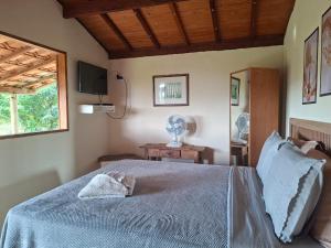 a bedroom with a bed with a blue blanket and a window at Pouso Canarinho in Carrancas