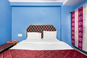 a blue bedroom with a bed with a red headboard at Hotel Swarna Mayuri in Guntūr