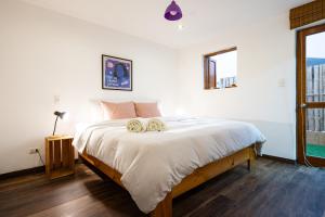 a bedroom with a bed with white sheets and a window at El Templo Surf House in Punta Hermosa