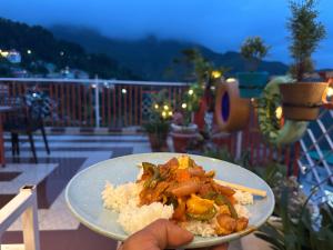 a person holding a plate of food with rice at Hotel Backpacers Mcleodganj in McLeod Ganj