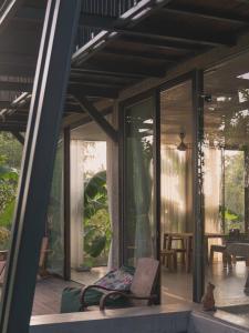 a house with glass doors and a chair on a porch at Chum Home in Thanh Ðông (1)