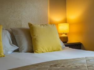 a bed with white pillows and a lamp on a table at Bagshaw Lodge in Bakewell