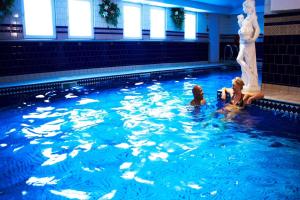 three children playing in a swimming pool next to a statue at The Spa Chalet Scarborough Hot tub, pool, gym, beach location in Scarborough