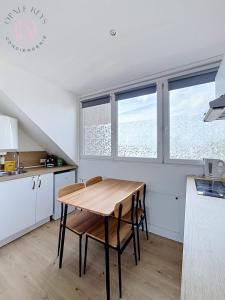 a kitchen with a wooden table and some windows at Le Studio Bleu - Dernier etage & Confort in Coudekerque-Branche