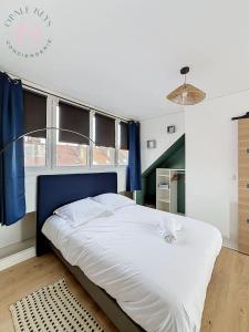 a bedroom with a large bed with a blue headboard at Le Studio Bleu - Dernier etage & Confort in Coudekerque-Branche