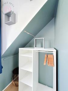 a white bookcase in a room with a staircase at Le Studio Bleu - Dernier etage & Confort in Coudekerque-Branche +5 photos