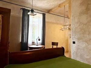 ein Schlafzimmer mit einem Bett, einem Tisch und einem Fenster in der Unterkunft K's Studio in Kuldīga