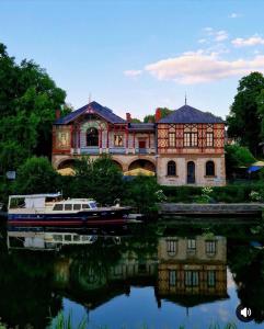 a large house with a boat in the water at Le Cocoon caché avec piscine parking,terrasse au calme appartement très frais ! in Sarreguemines