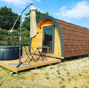 a cabin with an umbrella and a chair on a deck at Lodge des Bois Jacuzzi in Target +1 photo
