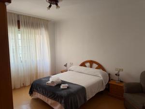 a bedroom with a bed and a chair and a window at Piso Super Espacioso en Cambados Centro in Cambados