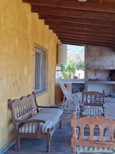 two wooden benches sitting on a porch with a hammock at Cabaña MariaMaria in Pomancillo +2 photos