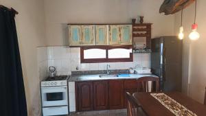a kitchen with wooden cabinets and a white stove top oven at Cabaña MariaMaria in Pomancillo