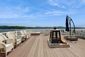 eine Terrasse mit Stühlen und einem Sonnenschirm am Wasser in der Unterkunft Loon Watch in Alton Bay