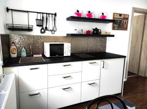 a kitchen with white cabinets and a microwave at Garden Home in Törökbálint +2 photos