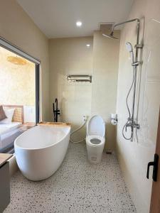 a bathroom with a white tub and a toilet at Sala Beach Villa Phú Quý in Cù Lao Thu