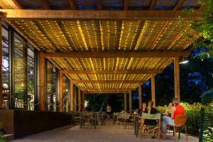 people sitting at tables under a pergola with lights at hu Firenze Certosa Camping in Town in Impruneta