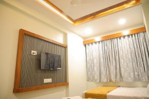 a bedroom with a tv and a window and a bed at Hotel Sumeet Palace in Shirdi