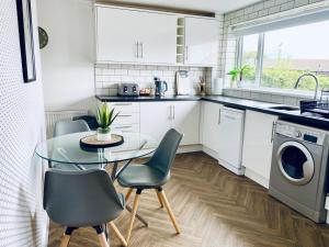 a small kitchen with a glass table and chairs at Foxcroft in Brighouse
