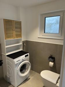 a bathroom with a washing machine and a toilet at Moderne Studio Oase in Donaueschingen +2 photos