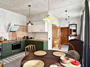 eine Küche mit einem Holztisch mit Stühlen und eine Küche mit grünen Schränken in der Unterkunft K's Studio in Kuldīga