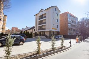 a building with cars parked in a parking lot at Jolie Boutique Hotel Corp B in Craiova