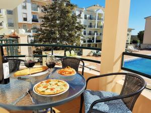 a table with two pizzas and wine glasses on a balcony at Solario da Praia holiday apartment in Armação de Pêra