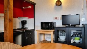 a kitchen with a tv on top of a cabinet at Duplex le Grimpeur - Les Apparts du Sancy in Chastreix +1 photo