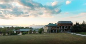 a house with a large yard in front of a building at Colonel's Resort in Bīr