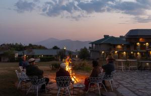 a group of people sitting around a fire in a yard at Colonel's Resort in Bīr