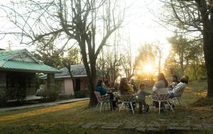 a group of people sitting at a table in a yard at Colonel's Resort in Bīr