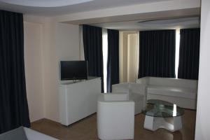 a living room with a couch and a television at Aegean Blue Beach Hotel in Nea Kallikrateia