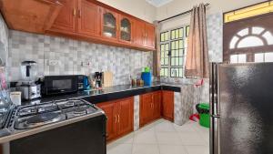 a kitchen with wooden cabinets and a black refrigerator at Hakika Homes in Olmotoni