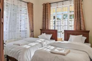 two beds in a room with two windows at Hakika Homes in Olmotoni