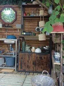 a kitchen with a sink and a shelf with dishes at THOUARS Rivière LODGE KAËLI in Maulais