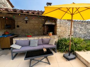a yellow umbrella and a purple couch on a patio at Grande chambre avec piscine in Villeneuve-sur-Vère