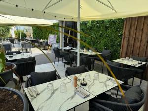 a restaurant with white tables and chairs and umbrellas at Hotêl - Restaurant Le Bon Duc in Les Billaux
