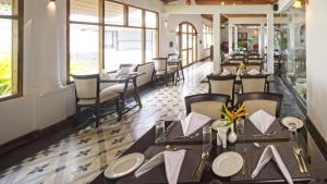 a dining room with tables and chairs and windows at Amritha Heritage in Trivandrum