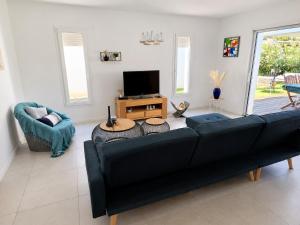 a living room with a black couch and a tv at Le Havre des Dunes in Brem-sur-Mer