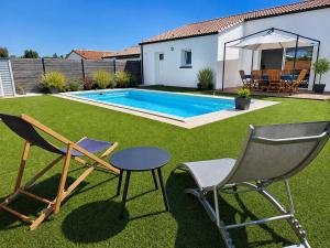 a yard with two chairs and a table and a swimming pool at Le Havre des Dunes in Brem-sur-Mer