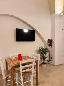 a dining room table with white chairs and a tv on the wall at Stella Apartment in Nardò