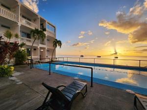 a resort pool with a bench and a view of the ocean at OE at Anchorage Hotel in Roseau