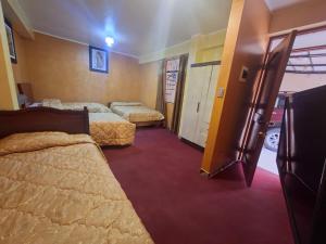 a hotel room with three beds and a red carpet at Hotel La Reserva INN in Ayacucho
