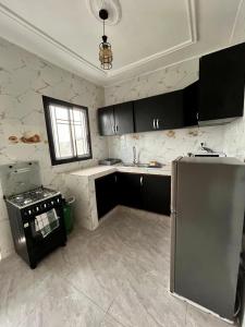 a kitchen with black cabinets and a stainless steel refrigerator at Western Suites in Douala
