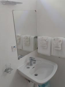 a white bathroom with a sink and a mirror at OE at Anchorage Hotel in Roseau +28 photos