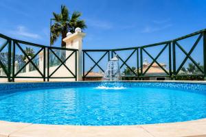 a swimming pool with a fountain in the middle at Grand Muthu Forte do Vale in Albufeira