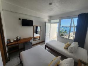 a room with two beds and a view of the ocean at OE at Anchorage Hotel in Roseau