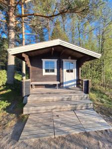 a small cabin with a bench on a wooden deck at Aijas Semesterstugor in Vaasa