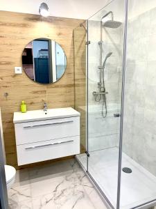 a bathroom with a shower and a sink and a mirror at Apartament z widokiem na las in Tychy