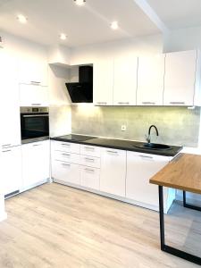 a kitchen with white cabinets and a wooden table at Apartament z widokiem na las in Tychy